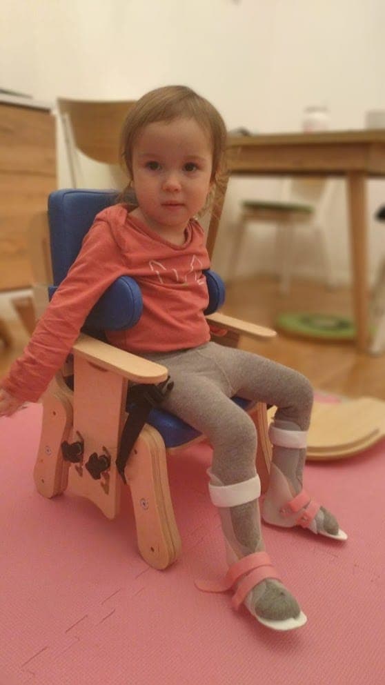Maryla siedzi w drewnianym krzesełku rehabilitacyjnym