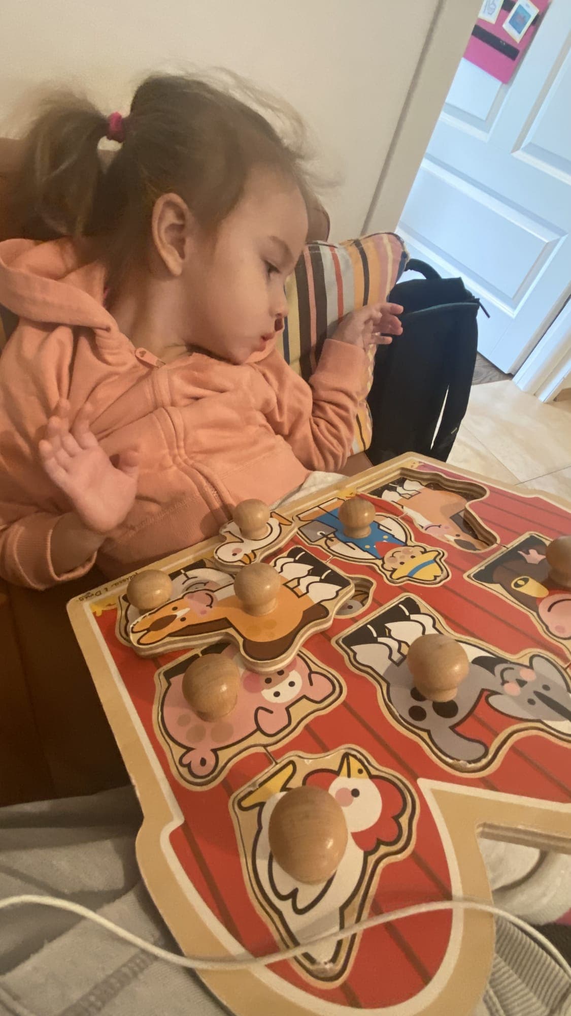Maryla w różowej bluzie układa drewniane puzzle