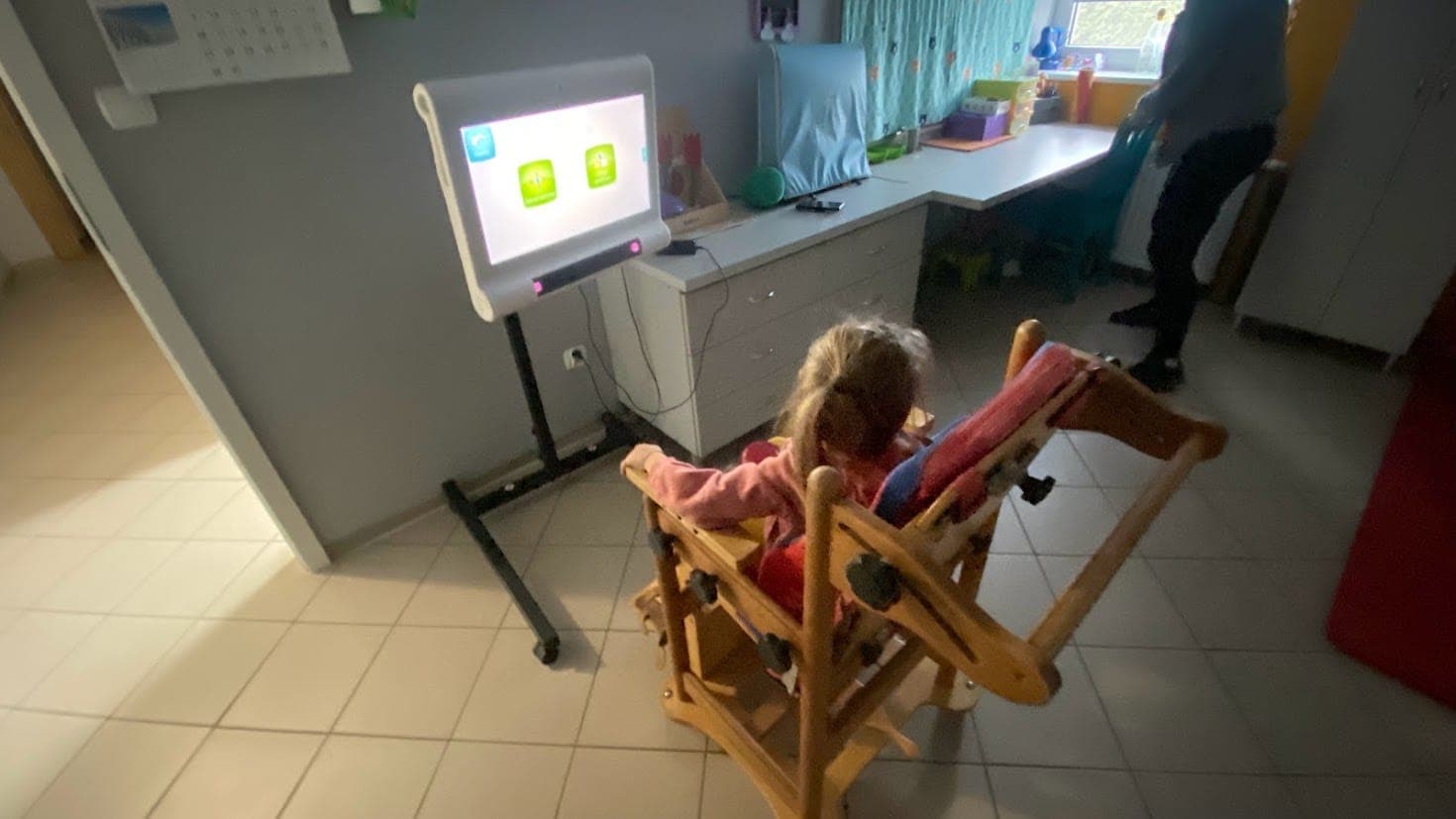 Maryla w specjalnym krzesełku przed ekranem z ćwiczeniami